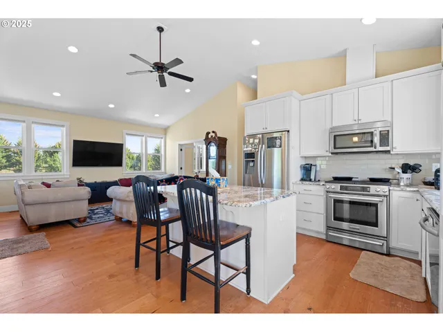 a living room with stainless steel appliances kitchen island furniture and a flat screen tv