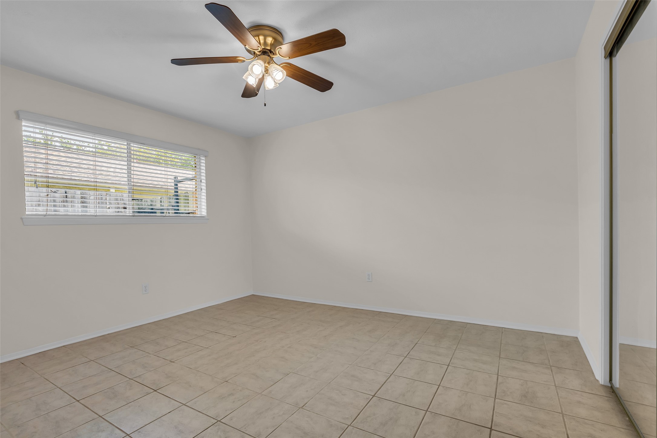 1447 Silverpines Road Houston, TX 77062 - Photo 13 of 17 Bedroom with neutral walls, tiled flooring, and a ceiling fan with lights. A window with blinds allows natural light, and there's a mirrored closet, providing storage.