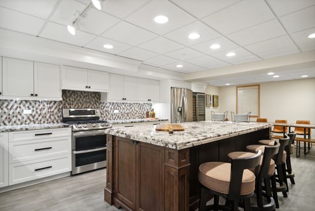 a kitchen with stainless steel appliances kitchen island granite countertop a table chairs sink and cabinets