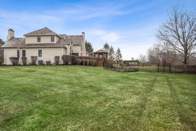 a view of a big house with a big yard and large trees
