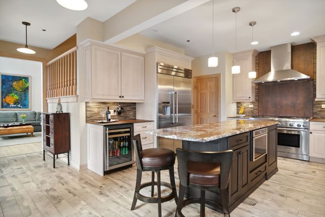 a kitchen with stainless steel appliances granite countertop a stove top oven a sink dishwasher and a refrigerator with wooden floor