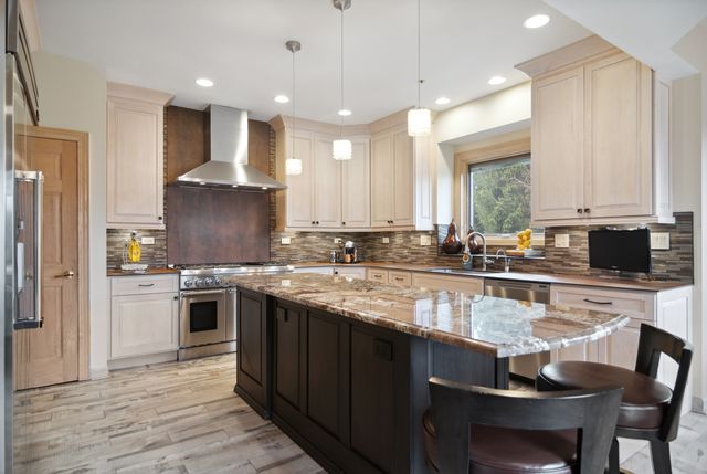 a large kitchen with granite countertop lots of counter top space and stainless steel appliances