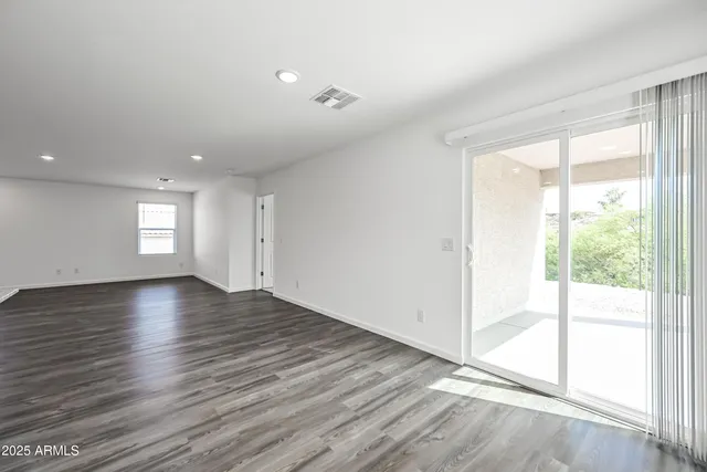 a view of empty room with window and wooden floor