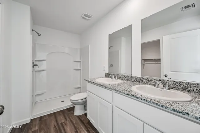 a bathroom with a granite countertop sink a toilet and shower