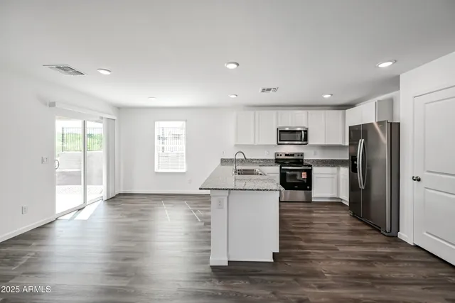 a kitchen with stainless steel appliances granite countertop a refrigerator a stove top oven a sink and dishwasher with wooden floor