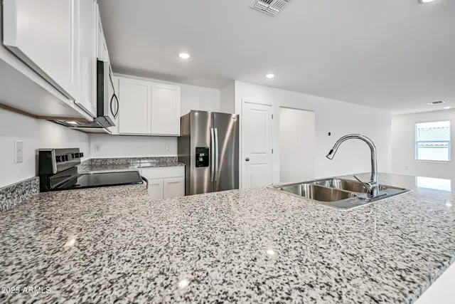 a kitchen with stainless steel appliances granite countertop a sink and a refrigerator
