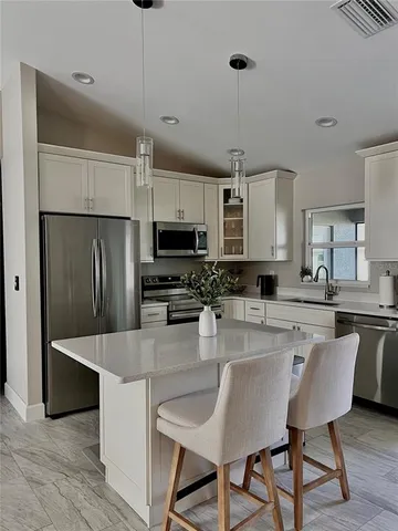 a large kitchen with kitchen island a large counter top space appliances and cabinets