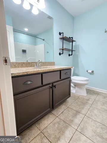 a bathroom with a granite countertop sink a toilet and mirror