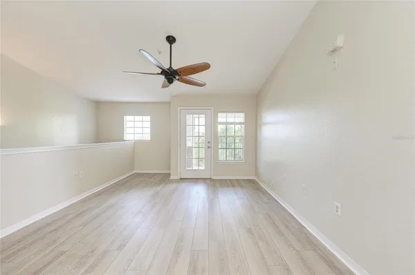 a view of empty room with wooden floor and fan