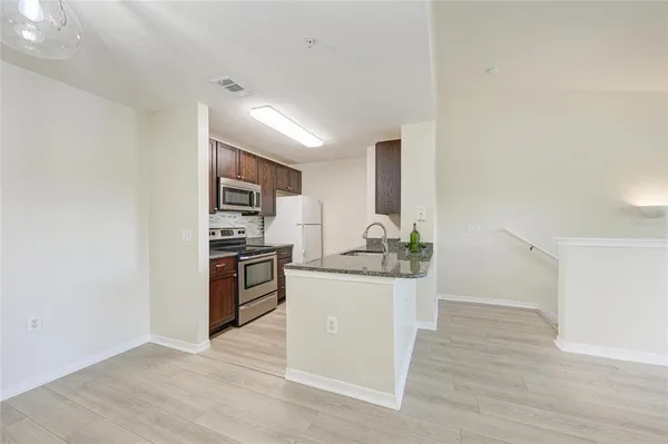 an empty room with wooden floor ceiling fan and windows