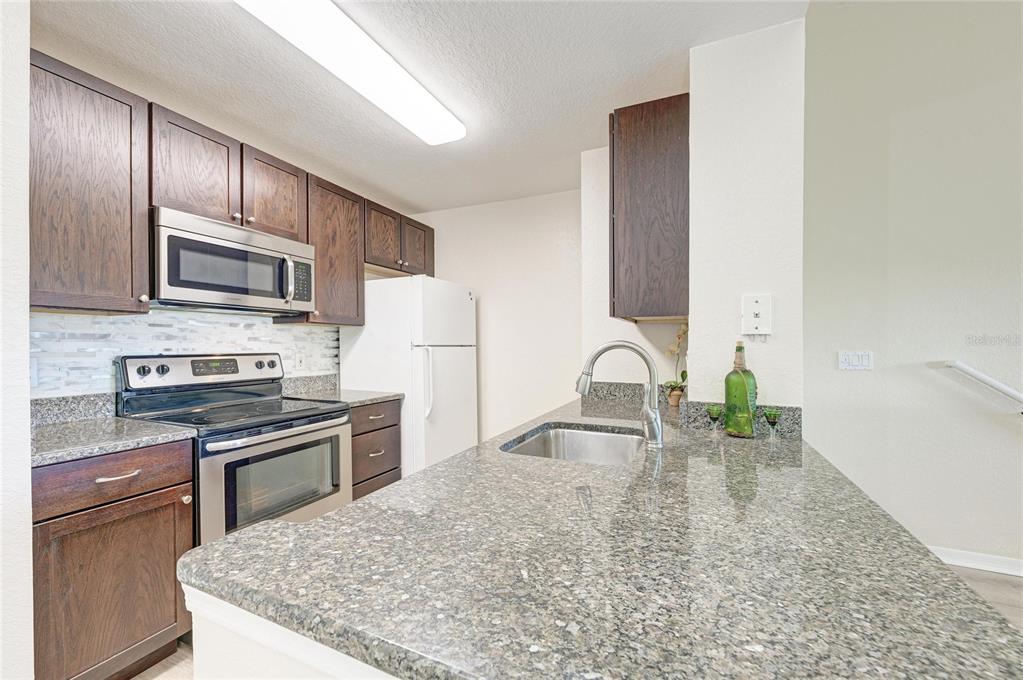 8911 Manor Loop, Unit 207 Lakewood Ranch, FL 34202 - Photo 28 of 71 a kitchen with stainless steel appliances granite countertop a sink stove and refrigerator