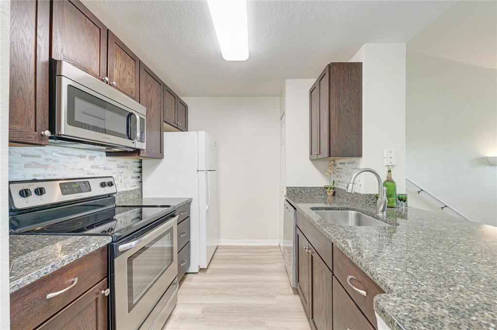 8911 Manor Loop, Unit 207 Lakewood Ranch, FL 34202 - Photo 30 of 71 a kitchen with stainless steel appliances granite countertop a sink stove and refrigerator