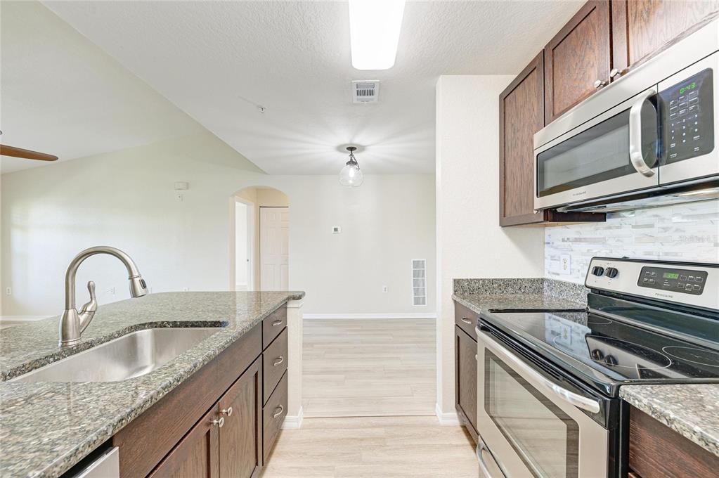 8911 Manor Loop, Unit 207 Lakewood Ranch, FL 34202 - Photo 31 of 71 a kitchen with granite countertop a sink and stainless steel appliances