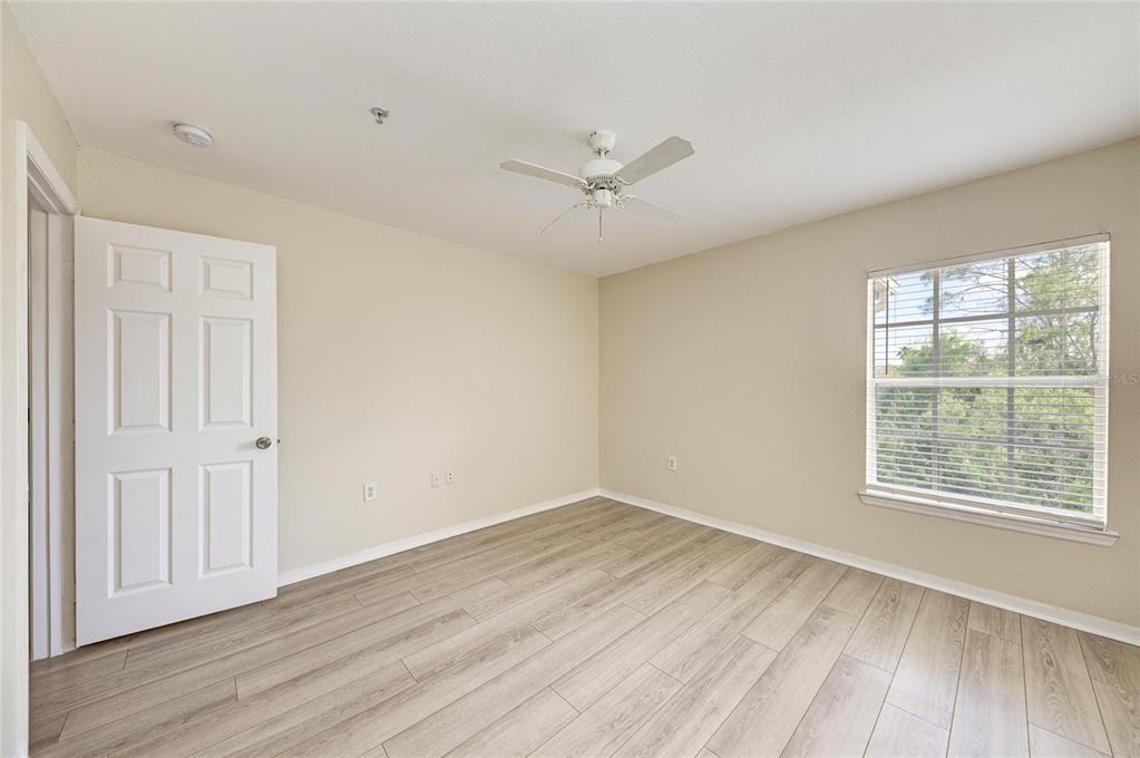 8911 Manor Loop, Unit 207 Lakewood Ranch, FL 34202 - Photo 34 of 71 an empty room with wooden floor ceiling fan and windows