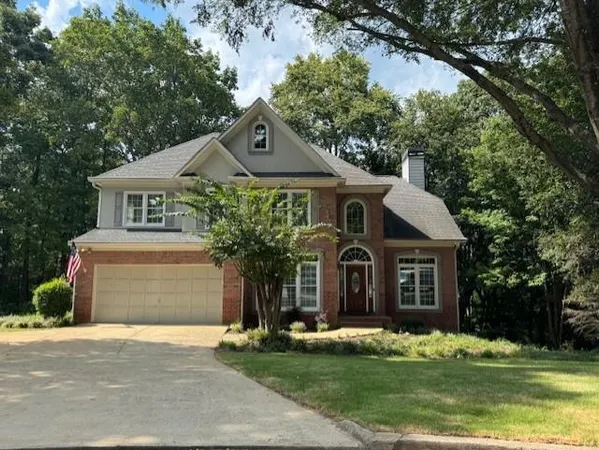 a front view of a house with a garden and trees