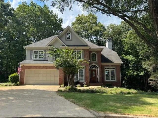 a front view of a house with a garden and trees