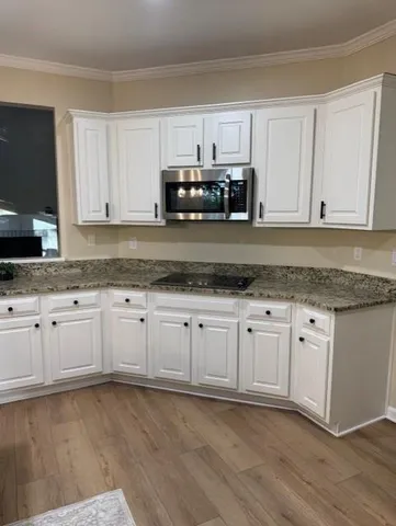 a kitchen with granite countertop white cabinets and stainless steel appliances
