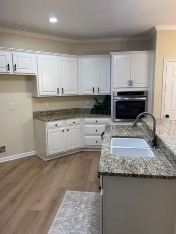 a kitchen with granite countertop a sink a stove and cabinets
