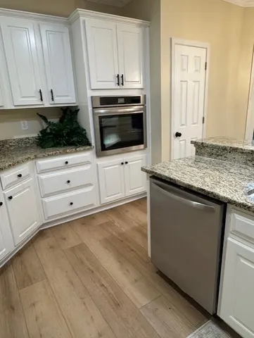 a kitchen with granite countertop white cabinets and stainless steel appliances