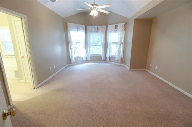 an empty room with windows and chandelier fan