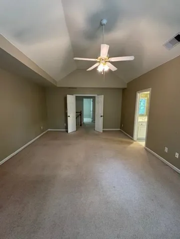 an empty room with chandelier fan and windows