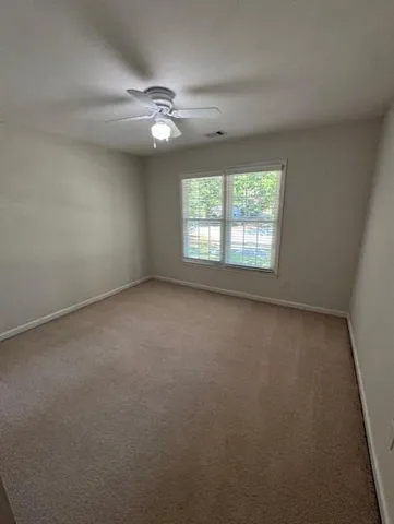 an empty room with a window and a fan