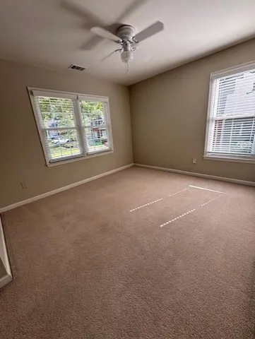 an empty room with windows and fan