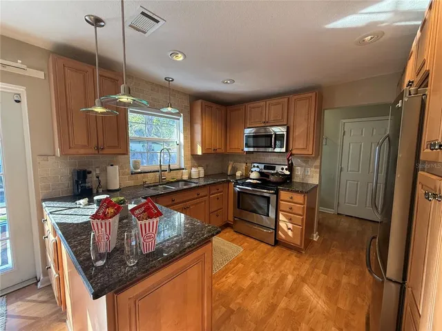 a kitchen with stainless steel appliances granite countertop a sink stove and refrigerator