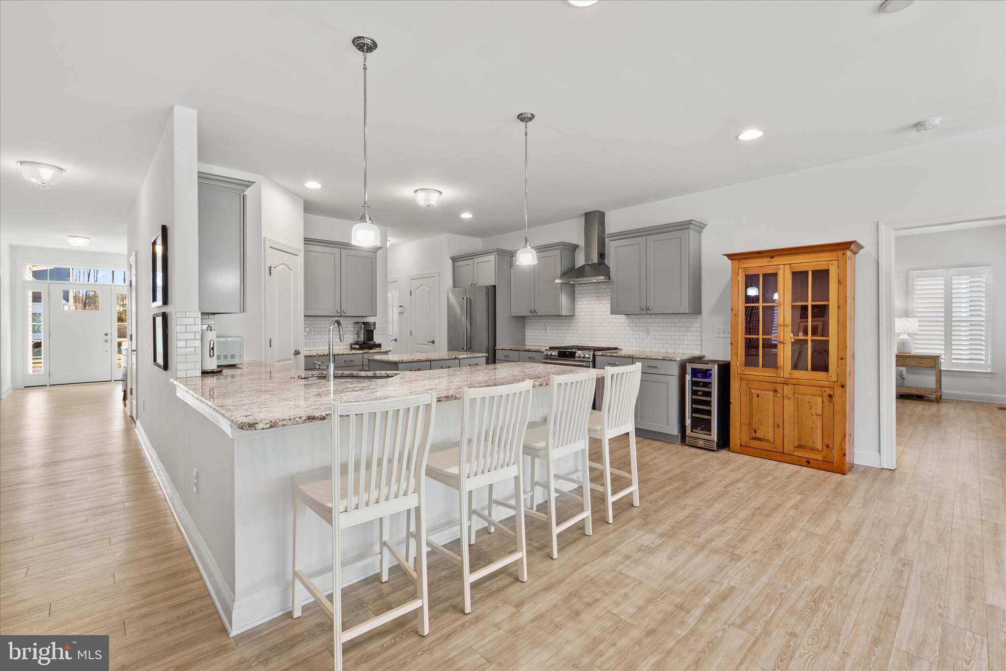 19181 Alcott Way Georgetown, DE 19947 - Photo 3 of 41 a large kitchen with kitchen island a dining table chairs and white cabinets
