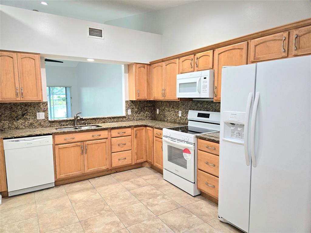 5912 Northwest 93rd Terrace Tamarac, FL 33321 - Photo 12 of 29 a kitchen with stainless steel appliances granite countertop a refrigerator sink stove and white cabinets