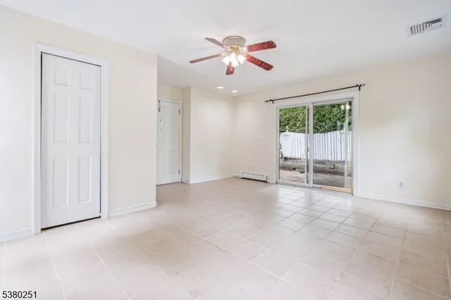 an empty room with chandelier fan and windows