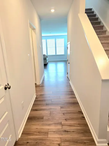 a view of a hallway with wooden floor and staircase