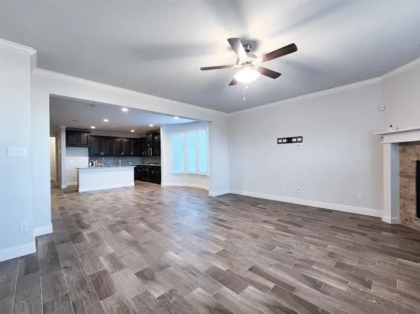 a view of empty room with wooden floor and ceiling fan