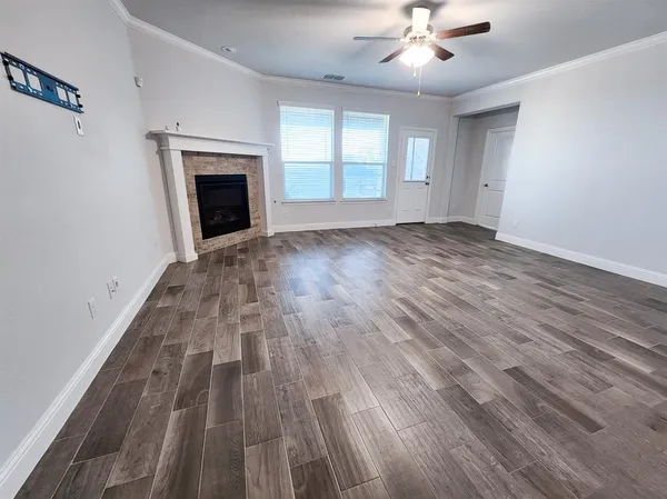 an empty room with wooden floor fireplace and windows