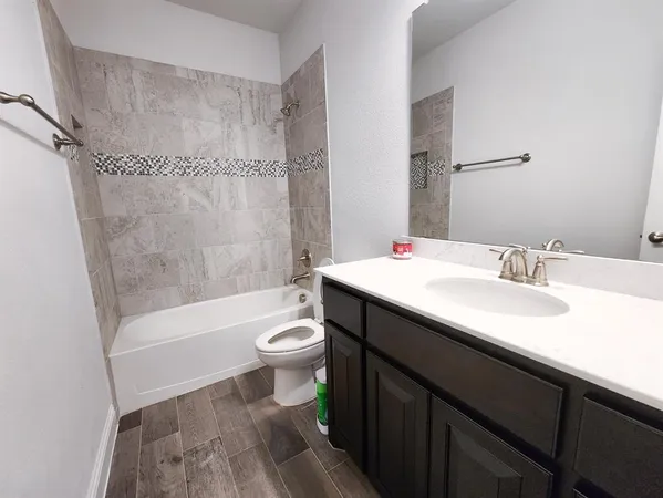 a bathroom with a sink a toilet a mirror a bathtub and shower