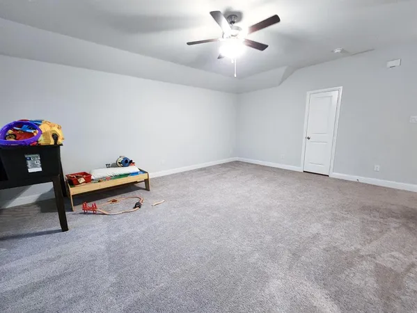 an empty room with ceiling fan and a wooden floor