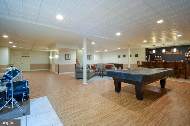 a kitchen with stainless steel appliances kitchen island granite countertop a refrigerator a stove a sink a dining table and chairs with wooden floor