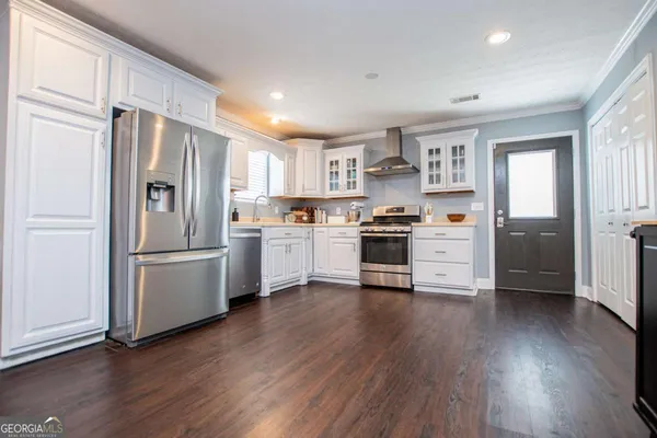 a kitchen with wooden floors and white stainless steel appliances