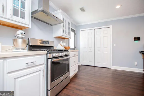 a kitchen with stainless steel appliances white cabinets and a wooden floors
