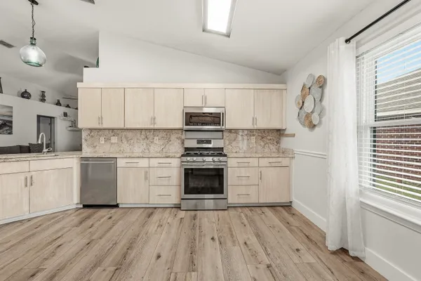 a kitchen with granite countertop a stove and white cabinets with wooden floors