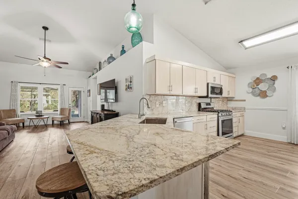 a large kitchen with cabinets appliances and a wooden floor