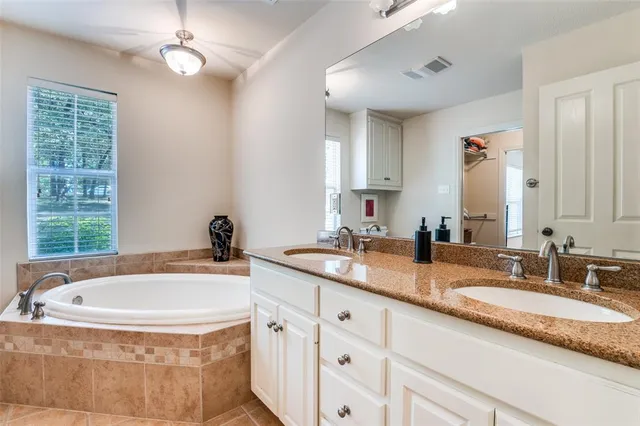 a bathroom with a granite countertop tub sink and mirror