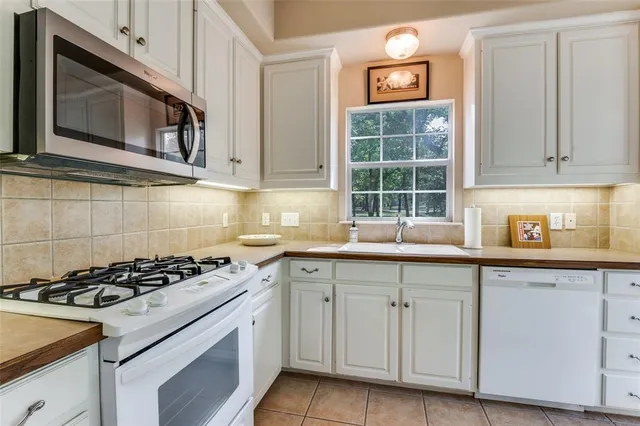 a kitchen with cabinets appliances a sink and a window