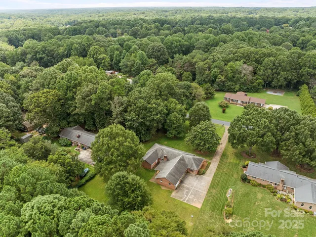 an aerial view of residential houses with outdoor space and trees