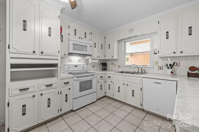a kitchen with granite countertop white cabinets white stainless steel appliances with a sink and dishwasher