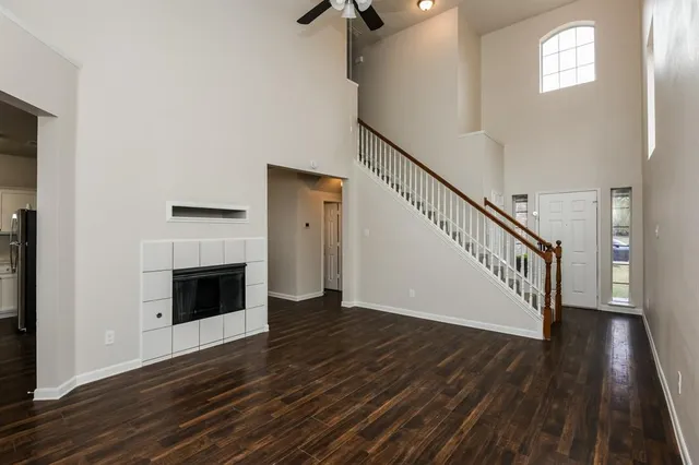 a view of an empty room with wooden floor fireplace and a window
