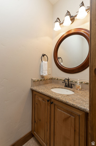 382 Ridgeview Street, Unit 8 & 9 Brian Head, UT 84719 - Photo 38 of 52 Bathroom vanity featuring a light-toned countertop, wood-finish cabinetry, an oval mirror with a wood frame, and a three-light fixture