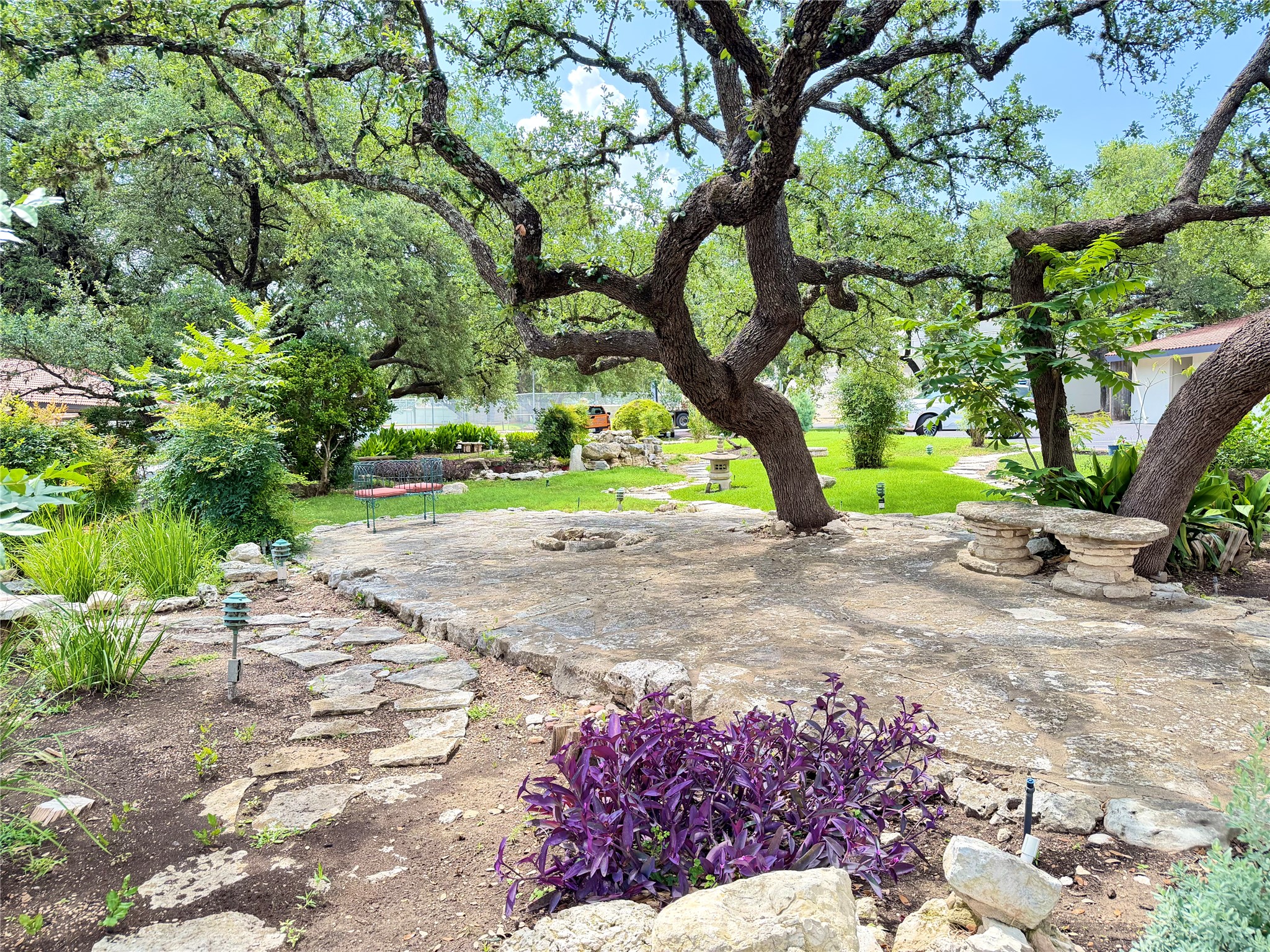2918 Ranch Road 620 North, Unit C120 Austin, TX 78734 - Photo 2 of 34 Mature trees canopy a serene outdoor area featuring a stone patio and garden paths.