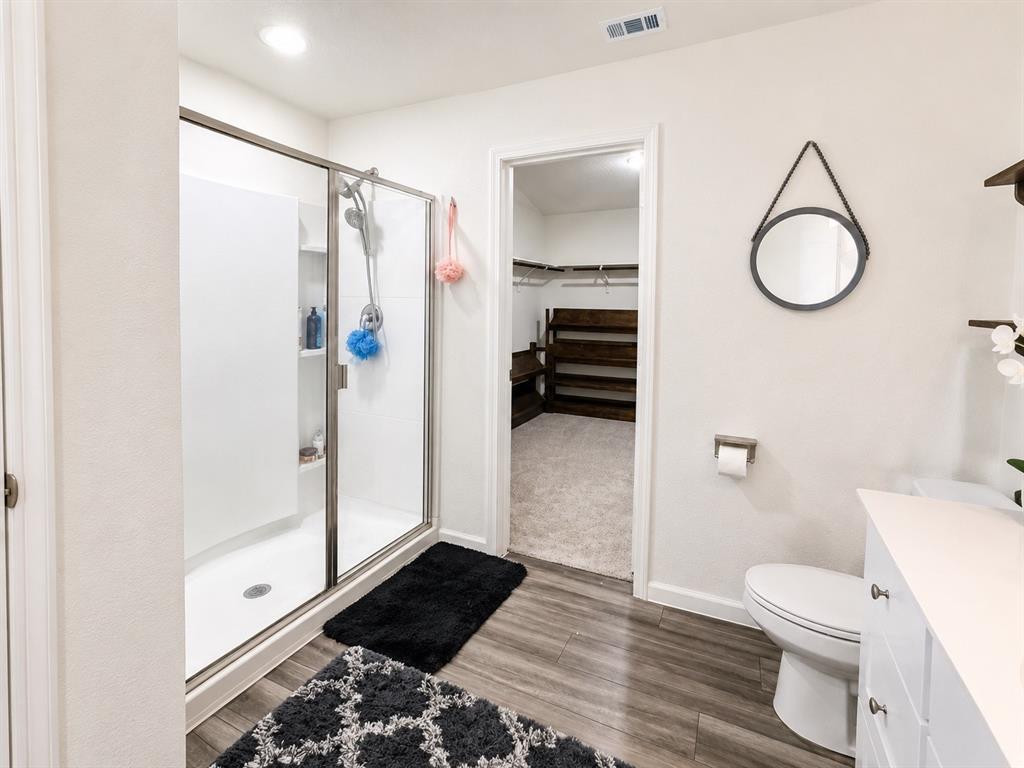 824 Juniper Street Anna, TX 75409 - Photo 18 of 25 Bathroom featuring a glass-enclosed shower with white subway tile, wood-finish flooring, and a white vanity with cabinet storage
