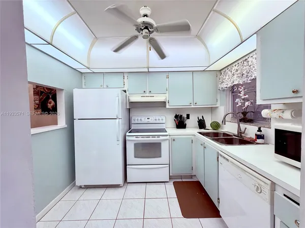 a kitchen with a white cabinets a refrigerator and a stove top oven